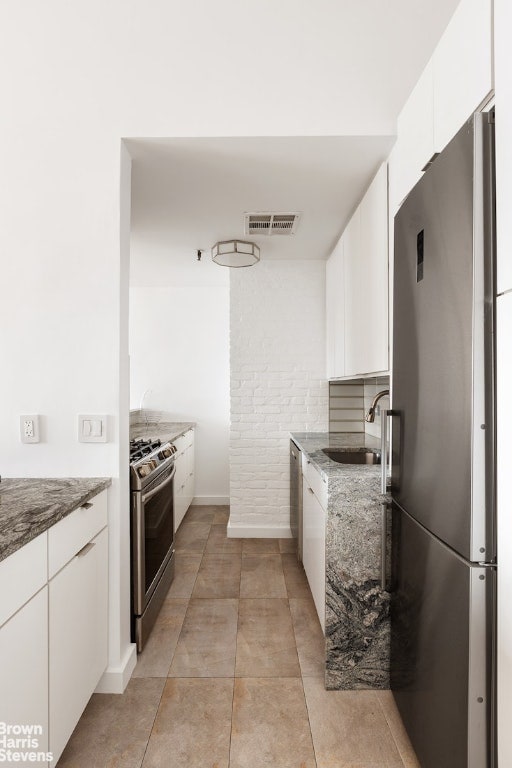 kitchen featuring sink, stone counters, white cabinets, and appliances with stainless steel finishes