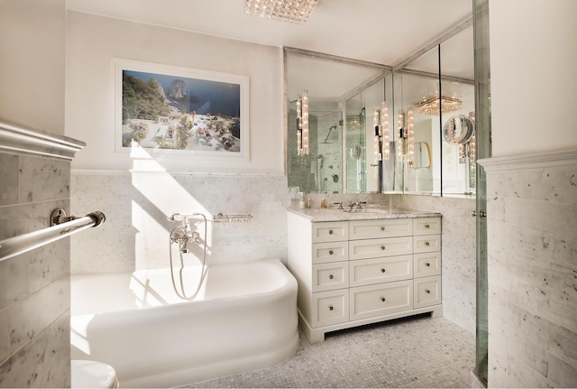 full bath featuring vanity, a bathtub, wainscoting, a stall shower, and tile walls