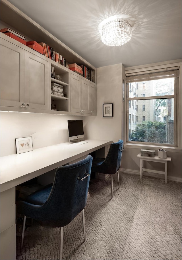 office space featuring built in desk, an inviting chandelier, and baseboards