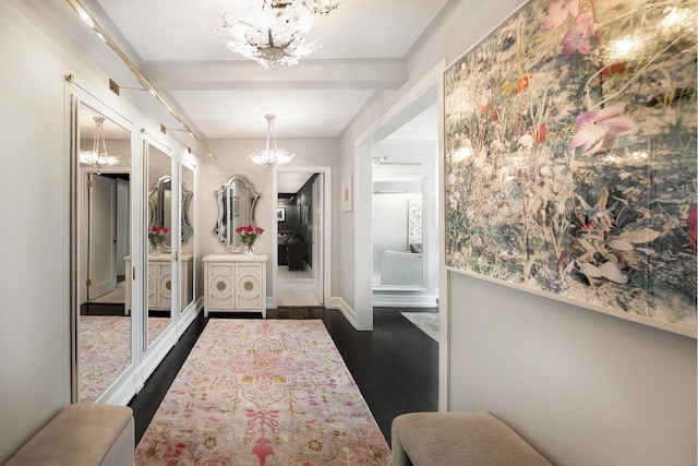 interior space with dark wood finished floors, an inviting chandelier, baseboards, and beam ceiling