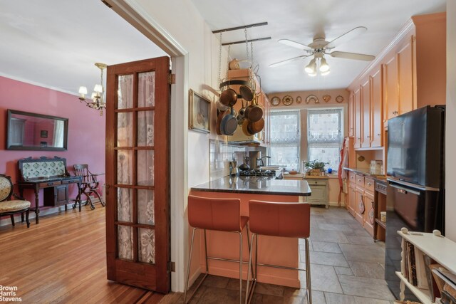 kitchen with black fridge, kitchen peninsula, a breakfast bar area, and light brown cabinets