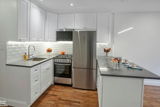 311 E 75th St Unit 3H, New York City, NY 10021 - kitchen with stainless steel appliances, a sink, a peninsula, white cabinetry, and recessed lighting