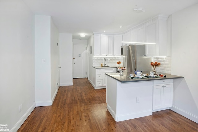 311 E 75th St Unit 3H, New York City, NY 10021 - kitchen featuring dark countertops, a peninsula, decorative backsplash, dark wood-type flooring, and recessed lighting
