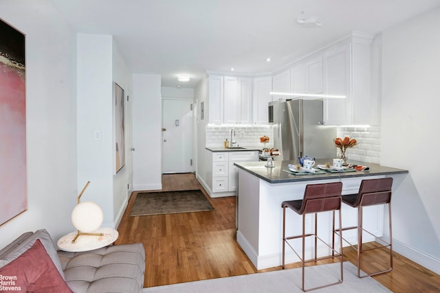 311 E 75th St Unit 3H, New York City, NY 10021 - kitchen featuring wood finished floors, freestanding refrigerator, white cabinetry, and recessed lighting