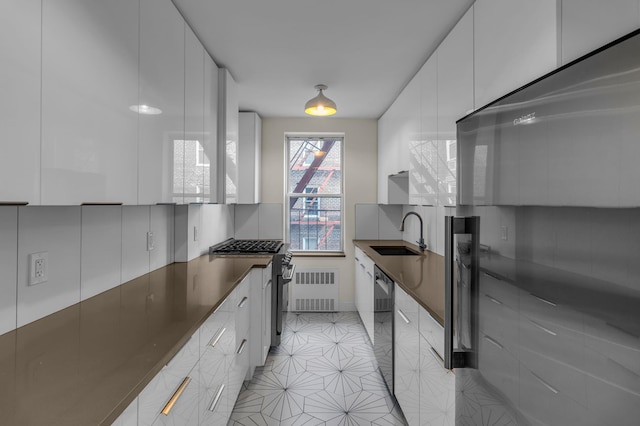 kitchen featuring radiator heating unit, a sink, decorative backsplash, appliances with stainless steel finishes, and modern cabinets