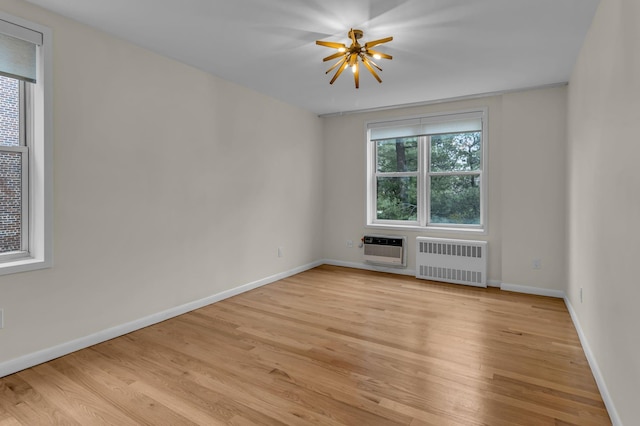 spare room featuring light wood-type flooring, heating unit, radiator, and plenty of natural light