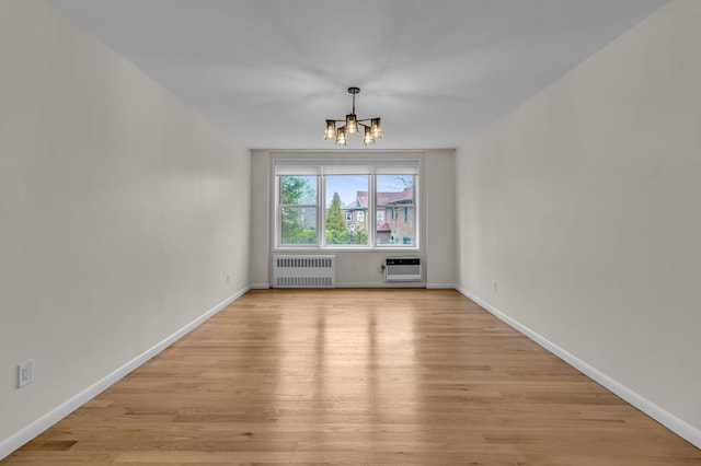 empty room featuring light wood-type flooring, baseboards, and radiator