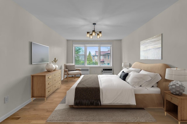 bedroom with light wood-type flooring, an AC wall unit, radiator, baseboards, and a chandelier