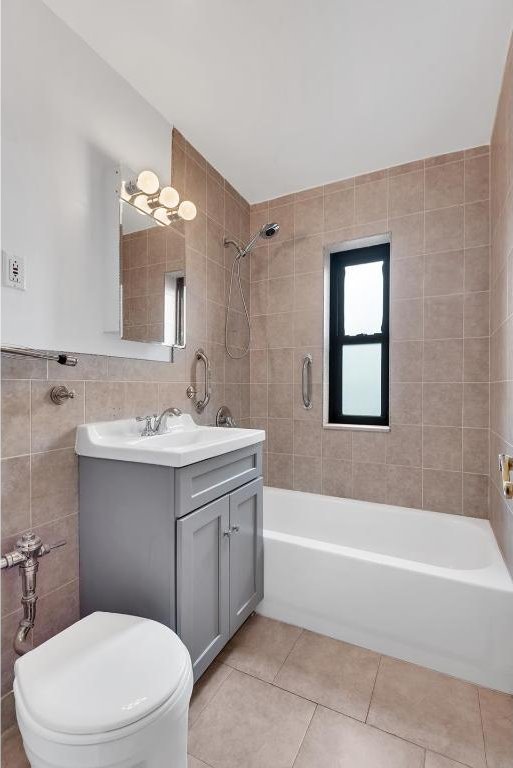 full bathroom with tile patterned floors, toilet, tile walls, vanity, and tiled shower / bath combo