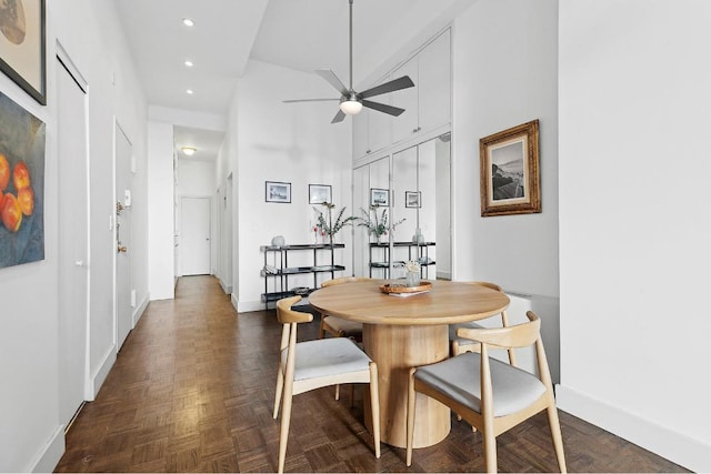 dining area with dark parquet flooring, a towering ceiling, and ceiling fan