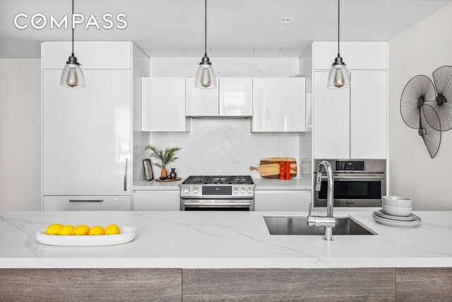 kitchen featuring a sink, white cabinetry, appliances with stainless steel finishes, modern cabinets, and pendant lighting