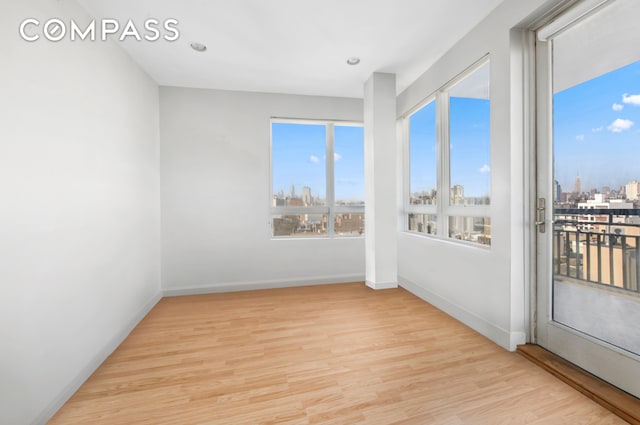 empty room with baseboards, a city view, and wood finished floors