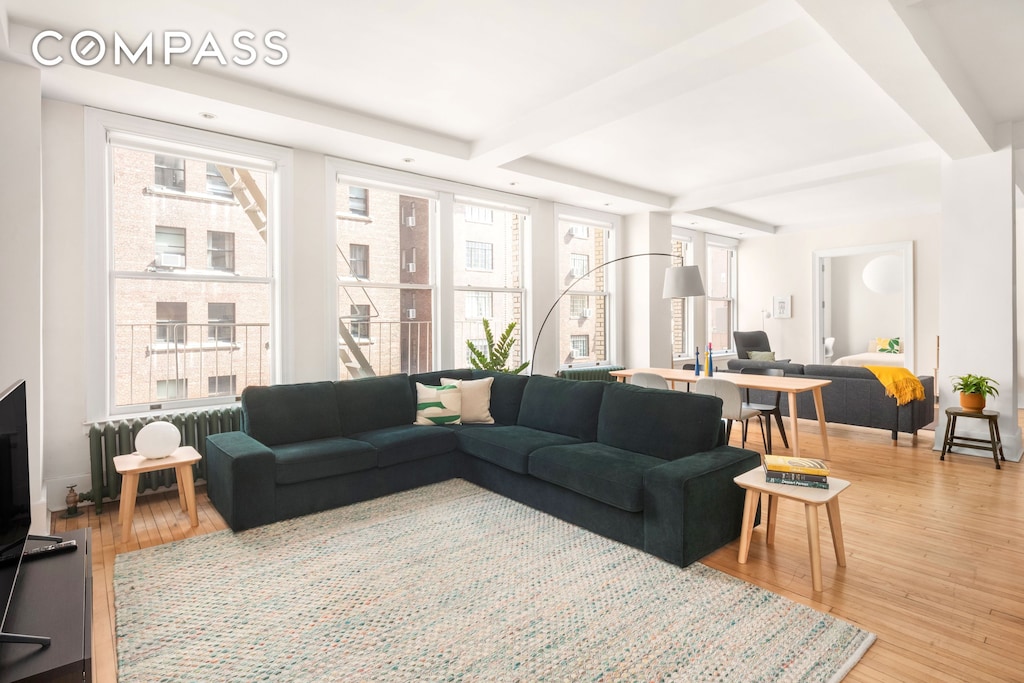 living room with beamed ceiling, radiator, and wood finished floors