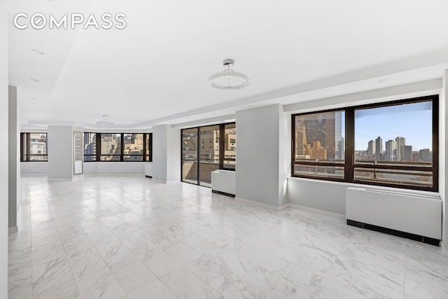 unfurnished room featuring a healthy amount of sunlight and radiator heating unit