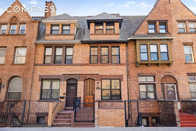 townhome / multi-family property featuring brick siding, fence, and roof with shingles