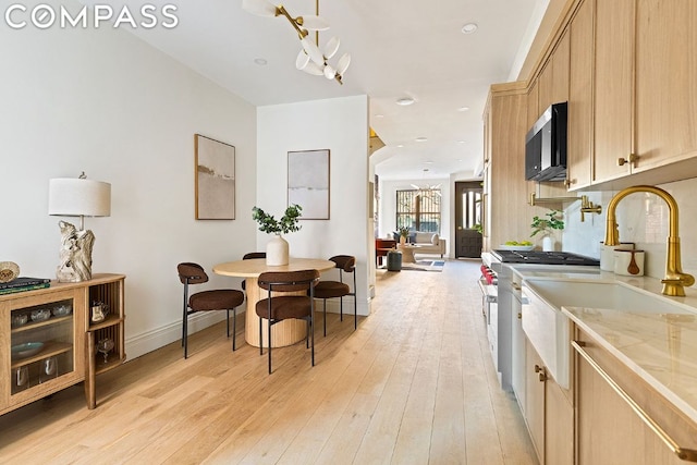 kitchen featuring appliances with stainless steel finishes, sink, light brown cabinetry, and light hardwood / wood-style floors