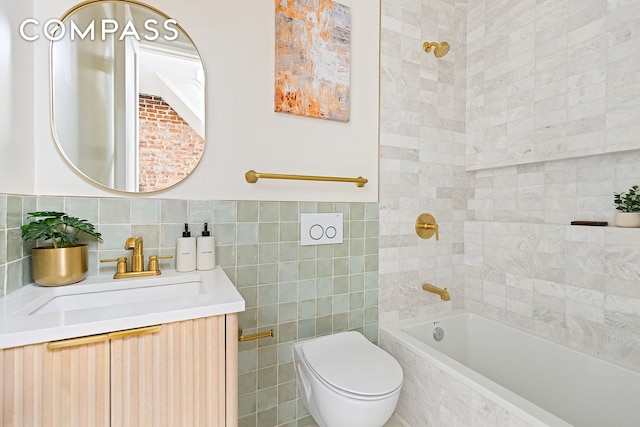 bathroom featuring tiled shower / bath, tile walls, toilet, and vanity