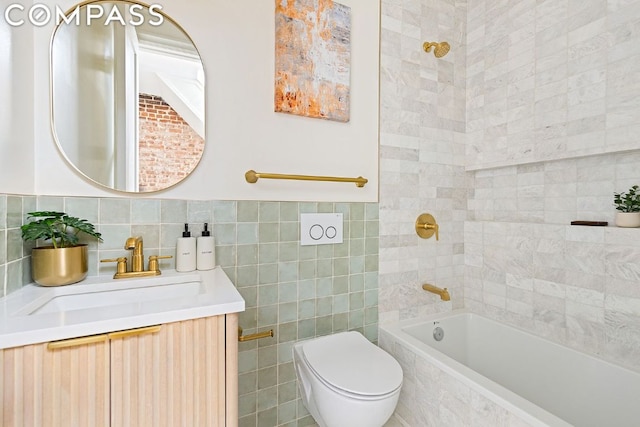 full bathroom featuring tiled shower / bath, tile walls, vanity, and toilet