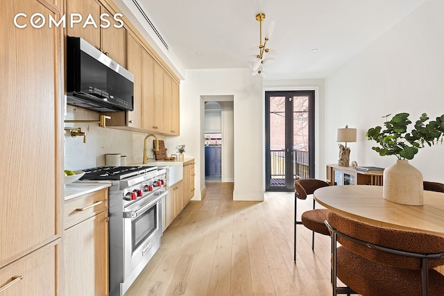 kitchen featuring light wood finished floors, stainless steel appliances, light countertops, french doors, and light brown cabinets