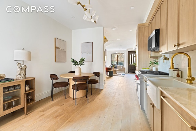 kitchen with light wood-type flooring, stainless steel appliances, a sink, and light brown cabinetry