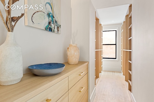 hallway featuring light wood finished floors and baseboards