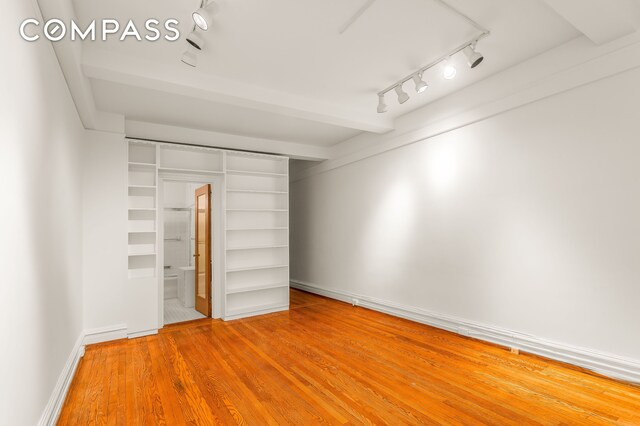 180 E 79th St Unit 5A, New York City, NY 10075 - unfurnished bedroom featuring track lighting, wood finished floors, and baseboards