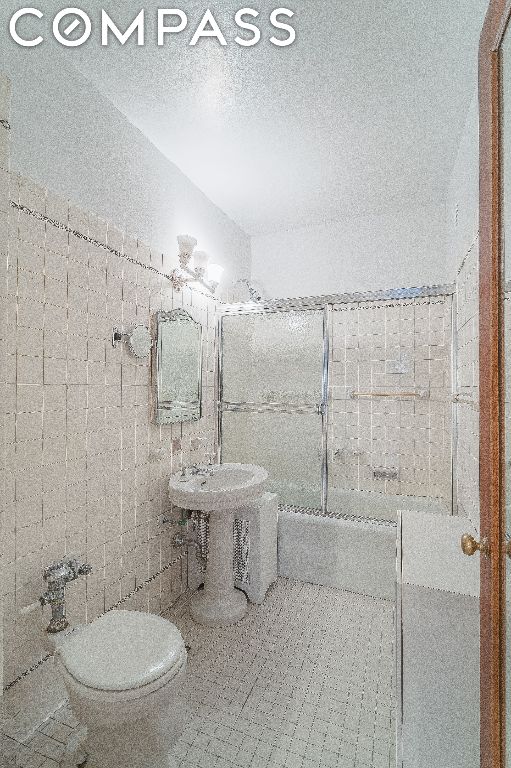 bathroom with toilet, tile patterned flooring, tile walls, and a textured ceiling