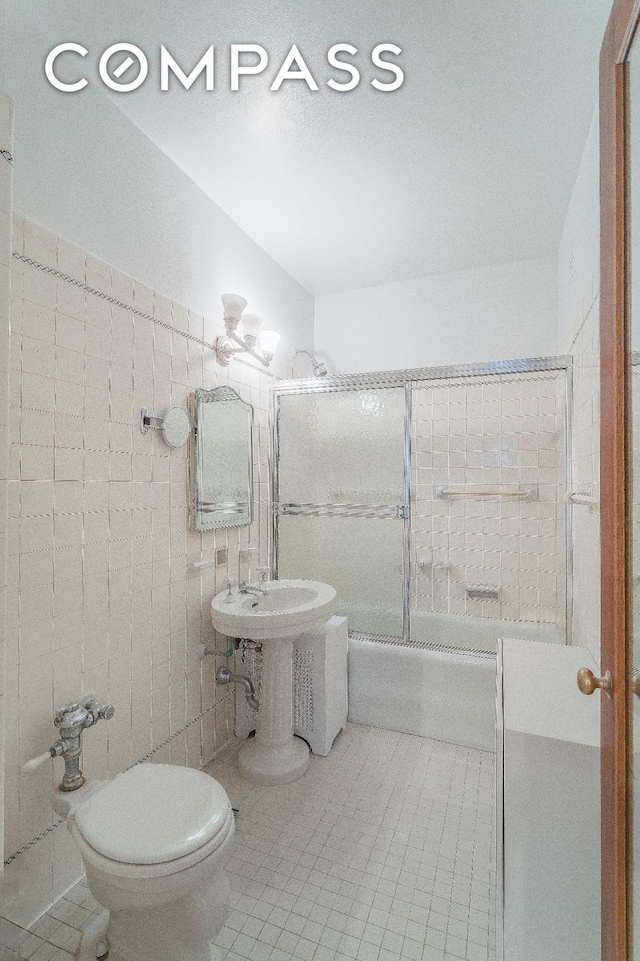 full bath featuring tile walls, enclosed tub / shower combo, tile patterned flooring, and toilet
