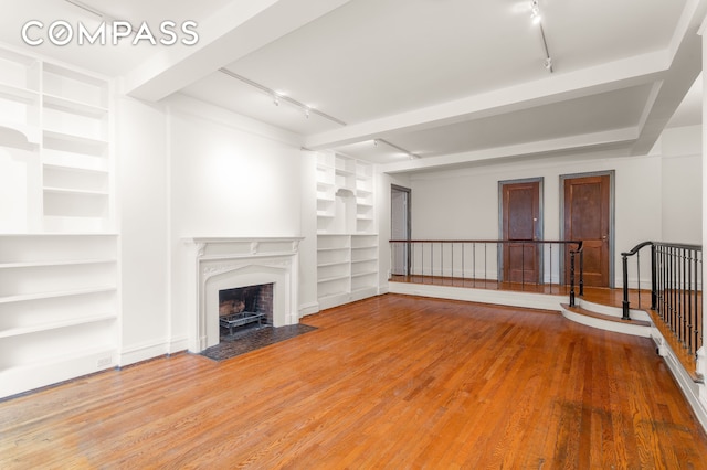 180 E 79th St Unit 5A, New York City, NY 10075 - unfurnished living room with track lighting, built in features, wood finished floors, and a fireplace with flush hearth