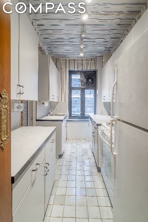 kitchen featuring white cabinetry, sink, and white appliances