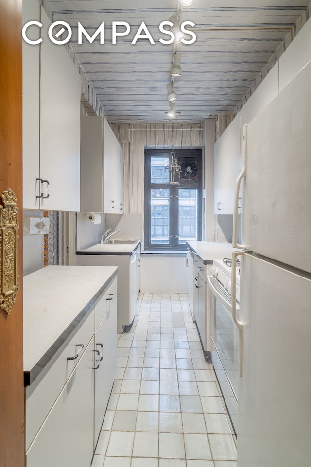 180 E 79th St Unit 5A, New York City, NY 10075 - kitchen featuring white appliances, white cabinets, light countertops, light tile patterned floors, and rail lighting