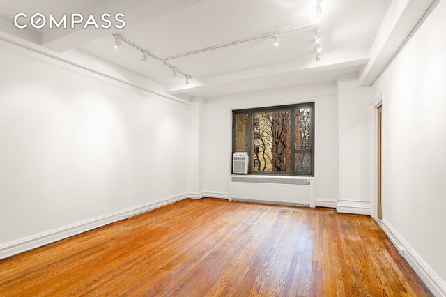 180 E 79th St Unit 5A, New York City, NY 10075 - empty room featuring track lighting, radiator, wood finished floors, baseboards, and cooling unit