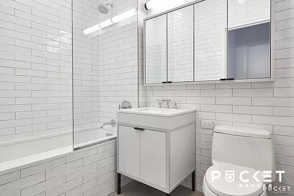 bathroom with tile walls, toilet, tiled shower / bath combo, vanity, and backsplash