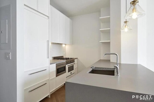 kitchen with a sink, white cabinets, decorative backsplash, open shelves, and decorative light fixtures