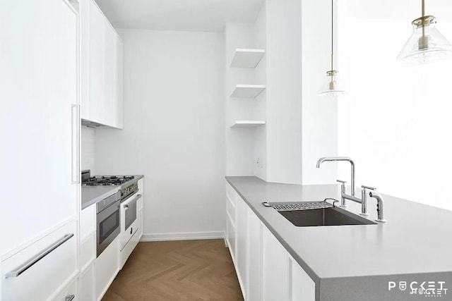 kitchen with high end stove, a sink, white cabinets, open shelves, and pendant lighting