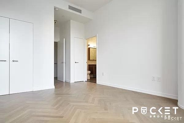 unfurnished bedroom with ensuite bathroom, a towering ceiling, visible vents, baseboards, and a closet