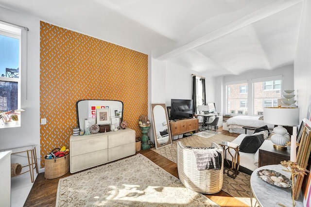 living room featuring beam ceiling, wallpapered walls, and wood finished floors