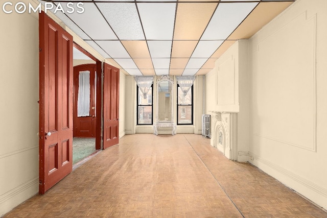 corridor with a paneled ceiling and light parquet flooring