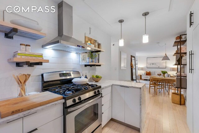 kitchen featuring gas stove, white cabinetry, decorative light fixtures, ventilation hood, and kitchen peninsula