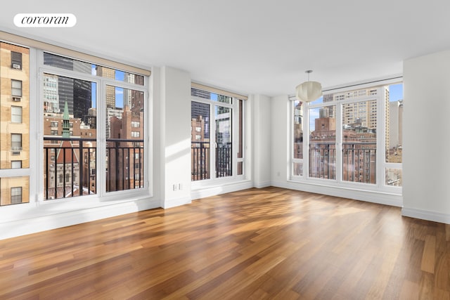 unfurnished room featuring baseboards, a city view, and wood finished floors