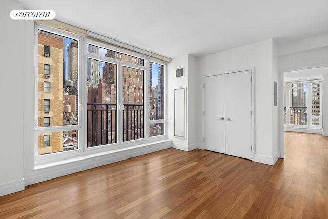 interior space with visible vents, wood finished floors, a view of city, baseboards, and a closet