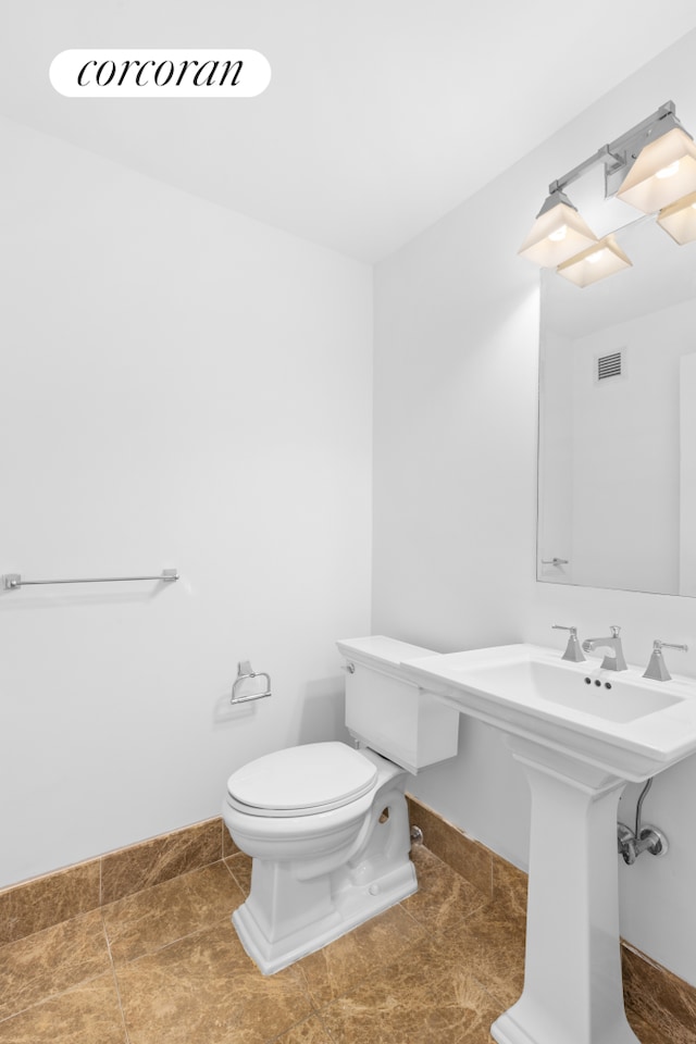 half bath featuring toilet, baseboards, and visible vents