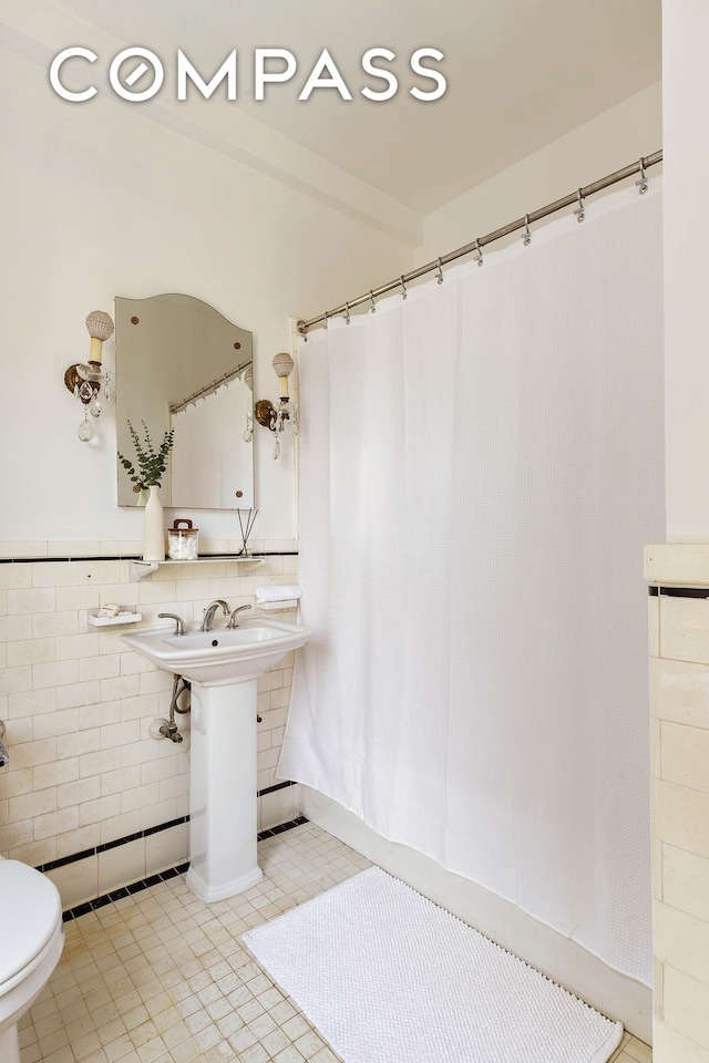 975 Park Ave Unit 10B, New York City, NY 10028 - full bathroom featuring tile walls, tile patterned floors, a shower with shower curtain, and wainscoting