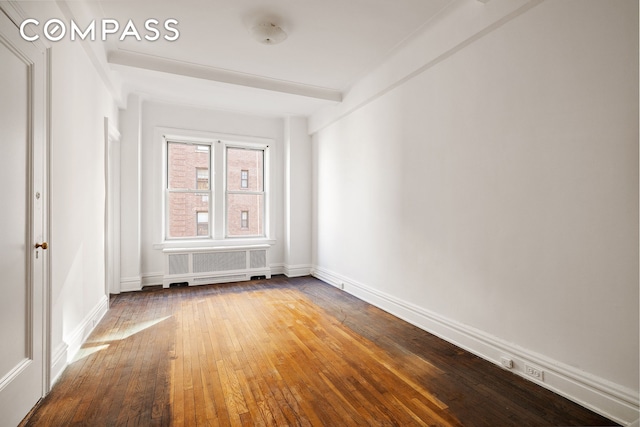 spare room with radiator, wood-type flooring, and baseboards