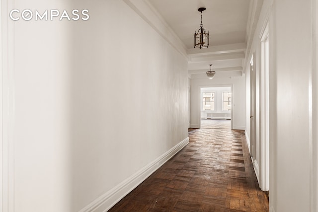 corridor featuring baseboards, a notable chandelier, and crown molding
