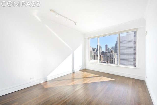 empty room with hardwood / wood-style flooring and ornamental molding