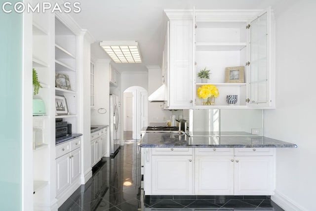 interior space featuring white cabinetry, extractor fan, stainless steel fridge, and dark stone counters