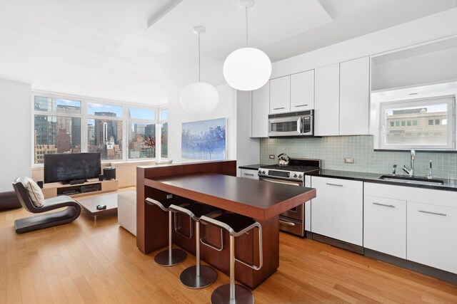 kitchen featuring light wood finished floors, dark countertops, a sink, and stainless steel appliances