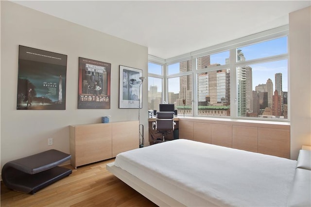 bedroom featuring light wood-type flooring and a city view