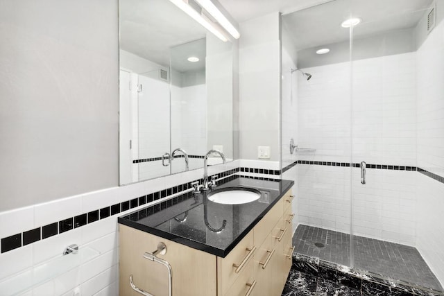 bathroom featuring vanity, tile walls, and walk in shower